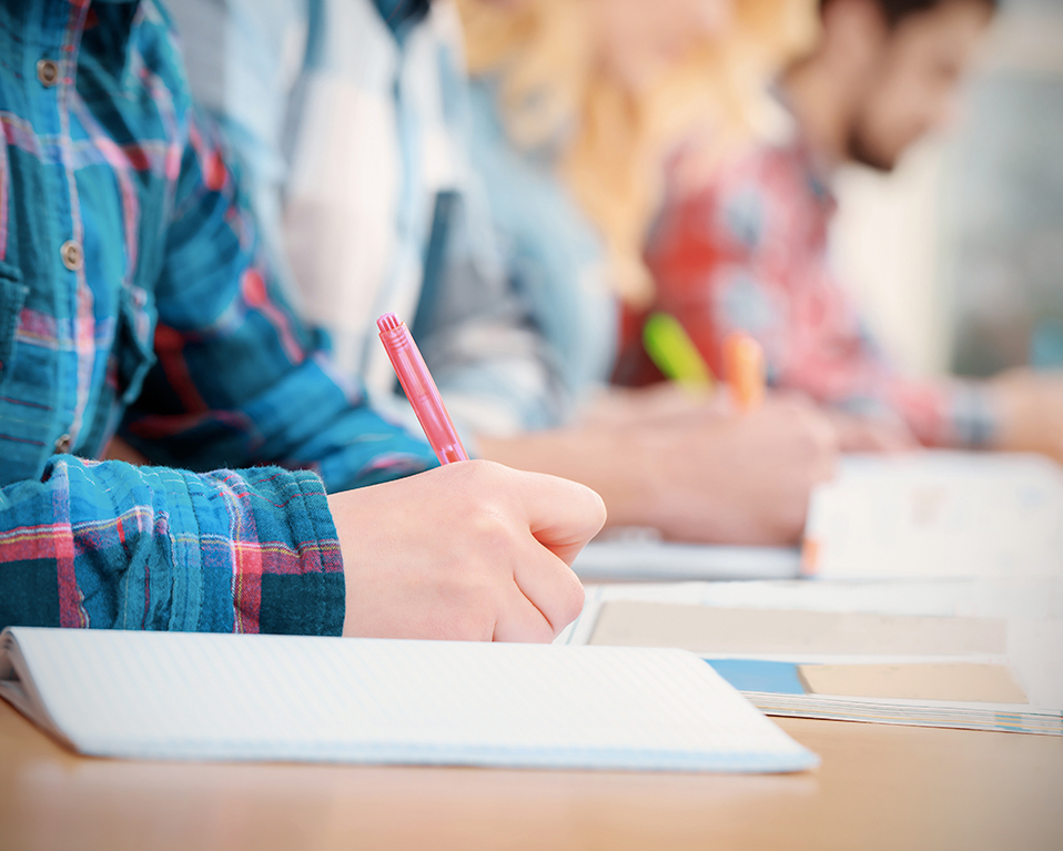 Estudiantes escribiendo apuntes mientras leen un libro