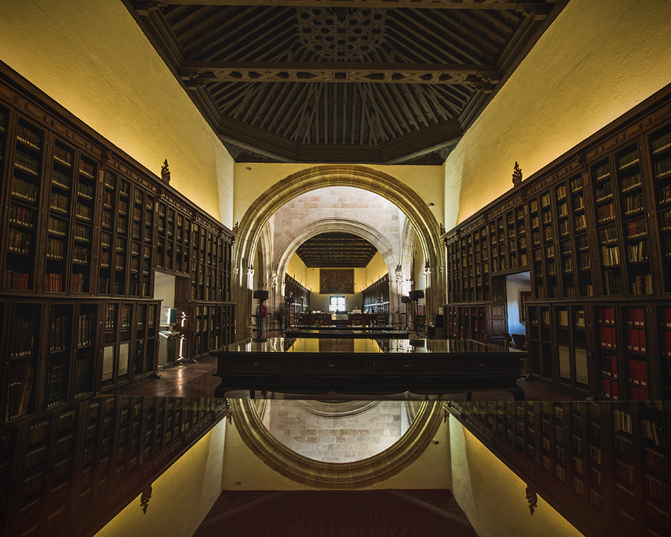 Pasillo biblioteca Hospital Real con mesas en el centro y estanterías con libros a ambos lados