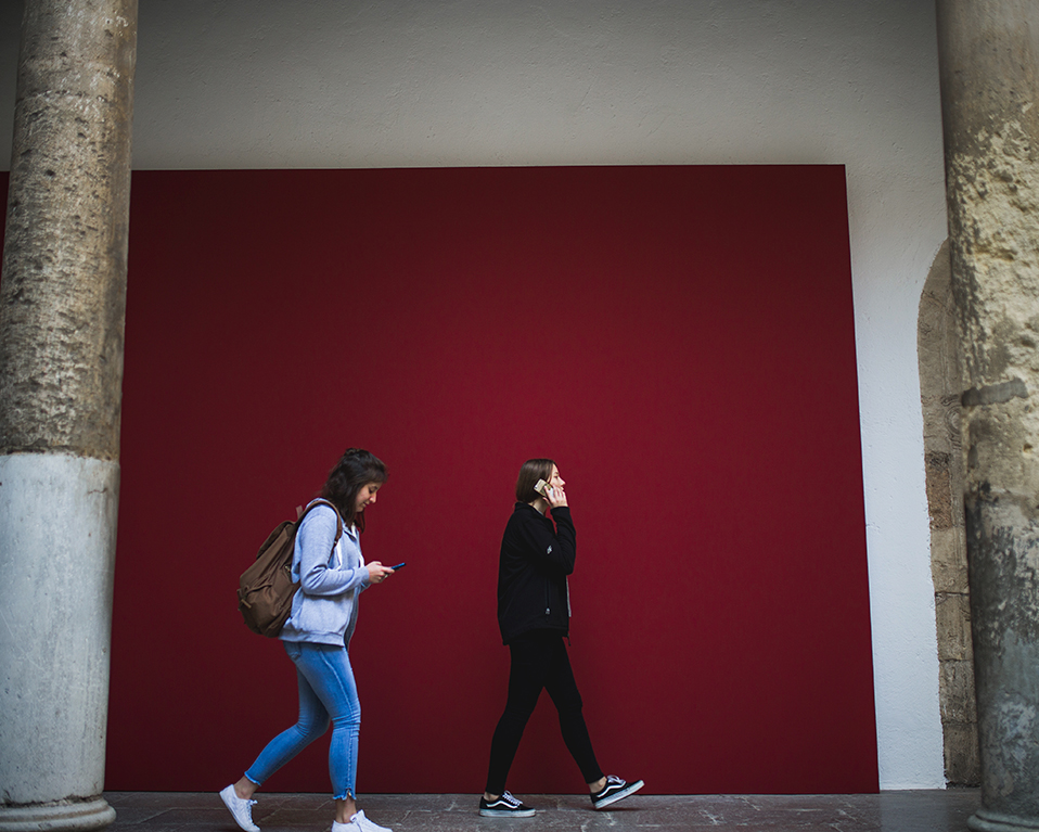 Dos estudientes caminando por uno de los patios del Hospital Real entre dos columnas