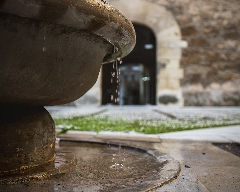 Fuente en patio del Hospital Real con puerta al fondo